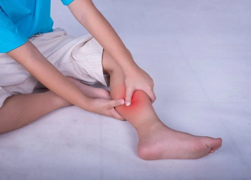 Trẻ ngồi ôm chân vì đau, mỏi chân